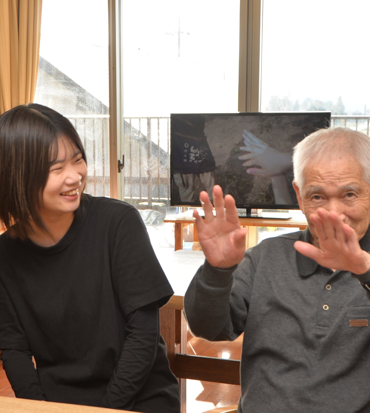 介護施設の共有スペースで高齢者とスタッフが穏やかに過ごす様子